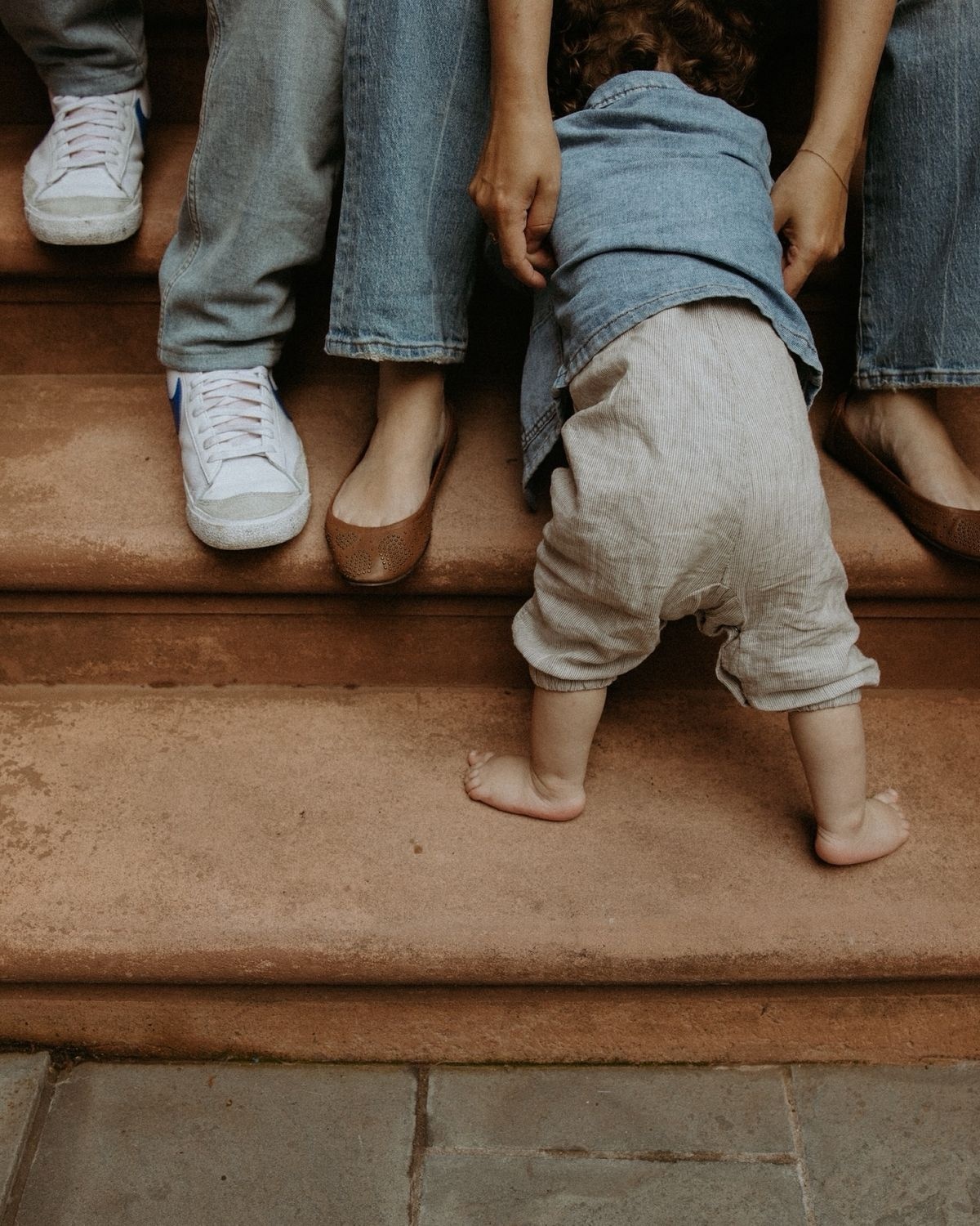 Toddler crawling down steps with parents sitting above